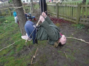 girl hanging on rope ladder outside